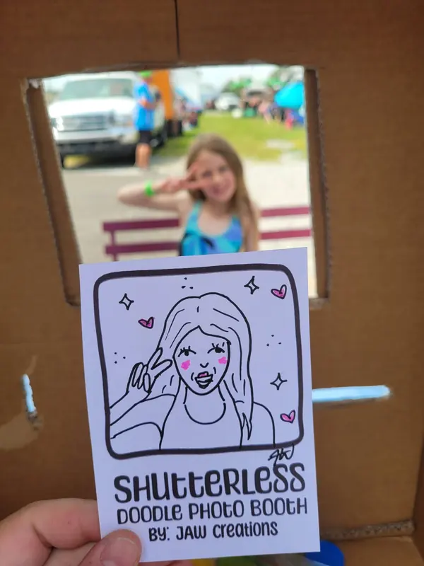 Girl posing in the booth frame beside her doodle portrait