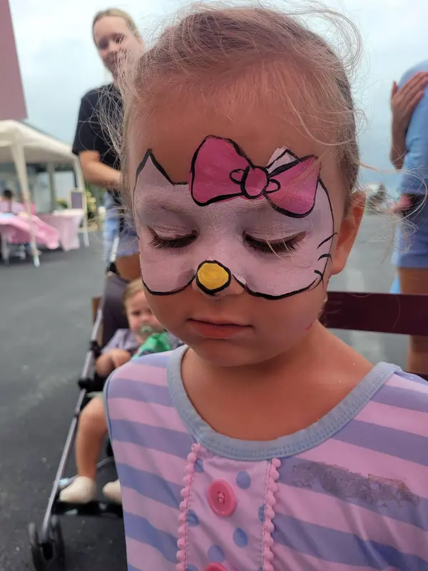 Child with a white kitty face design and pink bow