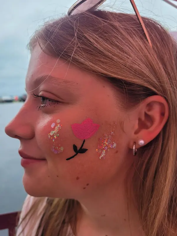 Rose and sparkles painted on a cheek