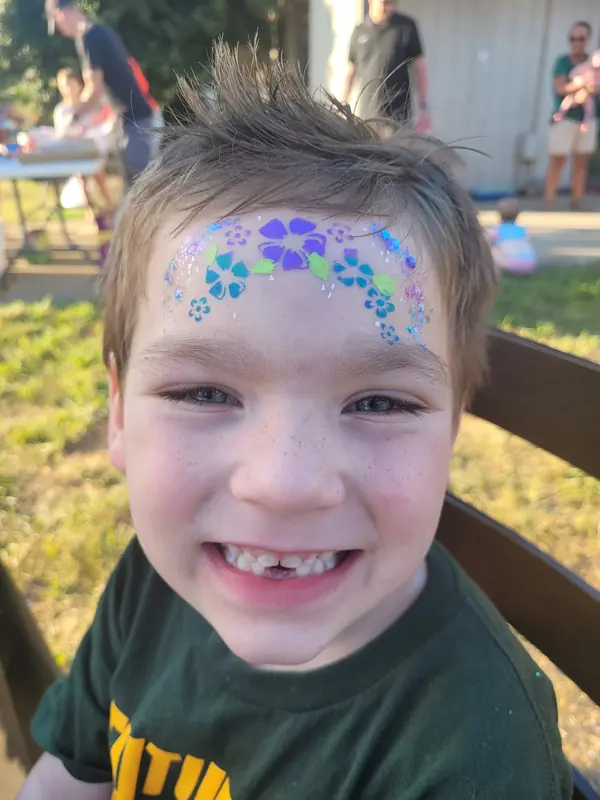 Child with a blue floral crown painted across the forehead