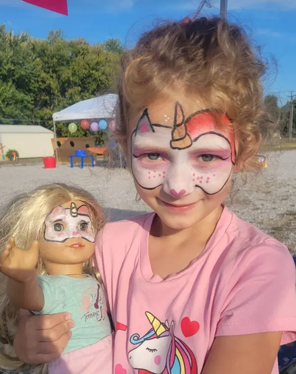 Girl and her doll with matching unicorn face paint