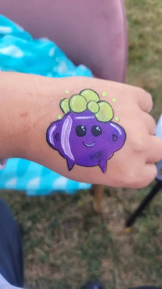 Purple grape character painted on a hand